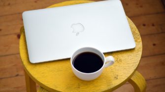 Macbook mit Kaffeetasse auf einem Hocker