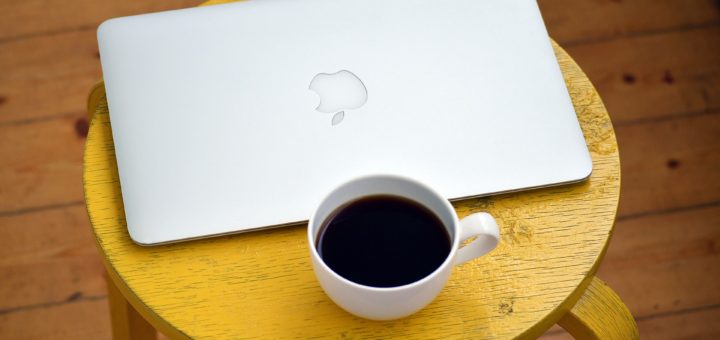 Macbook mit Kaffeetasse auf einem Hocker