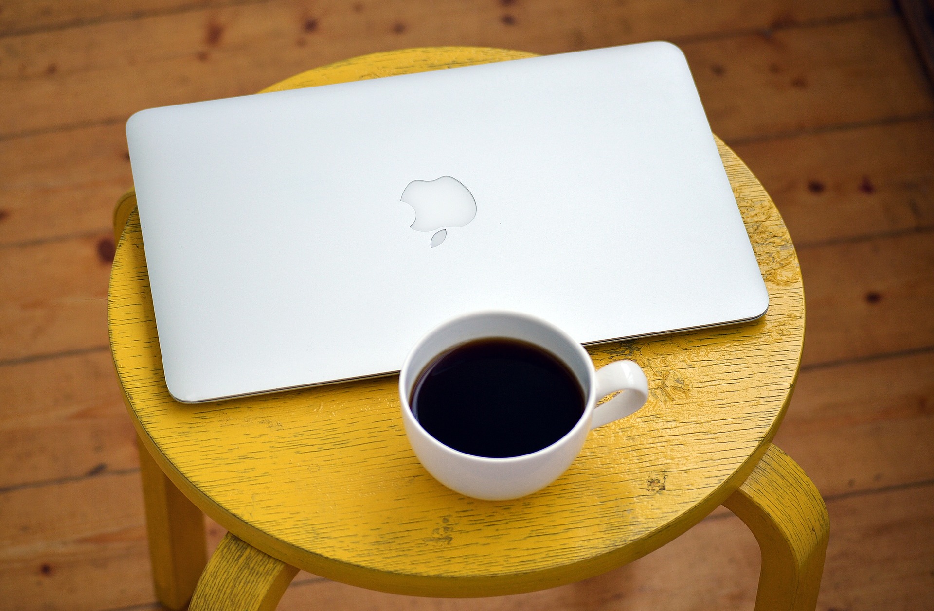 Macbook mit Kaffeetasse auf einem Hocker