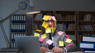 Geschäftsmann, bespickt mit Notizzetteln sitzt am Laptop spät in der Nacht