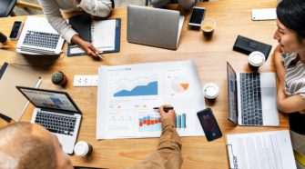 Gruppen-Meeting mit Laptops und Charts