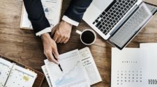 Monitoring Tools Blick auf einen Schreibtisch mit Laptop und Dokumenten