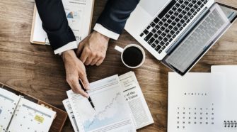Monitoring Tools Blick auf einen Schreibtisch mit Laptop und Dokumenten