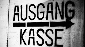 Weißes Hinweisschild für Kasse und Ausgang