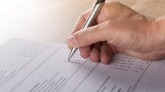Frageborgen nach Muliple-Choice-Prinzip wird von einer Hand mit Kugelschreiber ausgefüllt