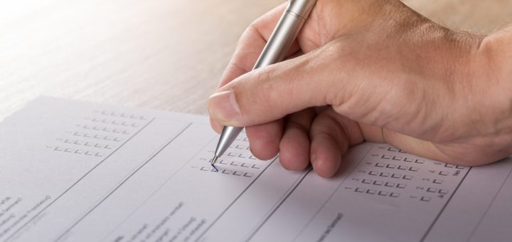 Frageborgen nach Muliple-Choice-Prinzip wird von einer Hand mit Kugelschreiber ausgefüllt